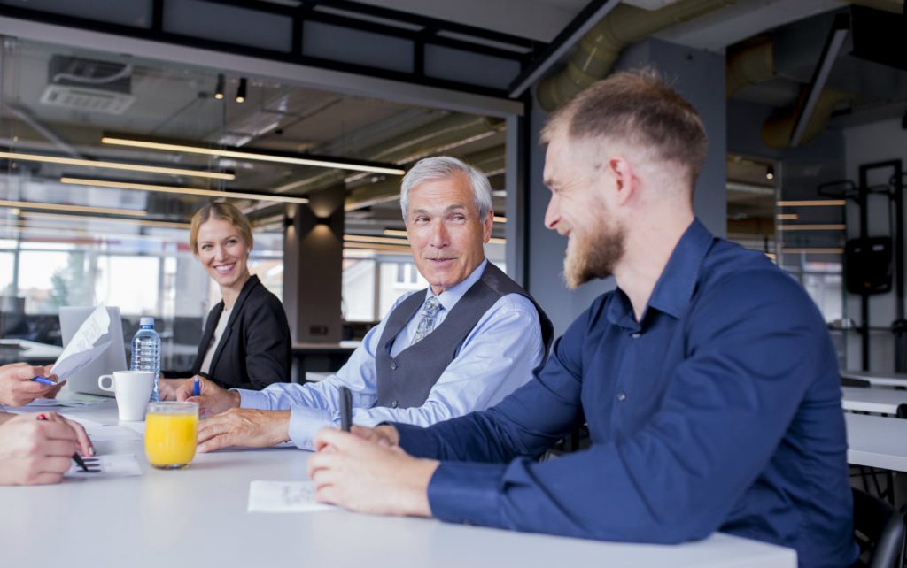 Como manter o foco da equipe: mesa de reunião com chefe e funcionário conversando amigavelmente.